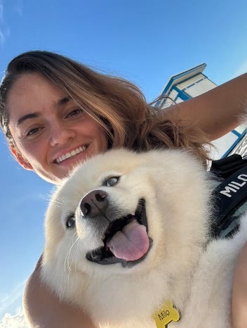 Camila García Naranjo junto a un perro blanco de pelo largo, al aire libre