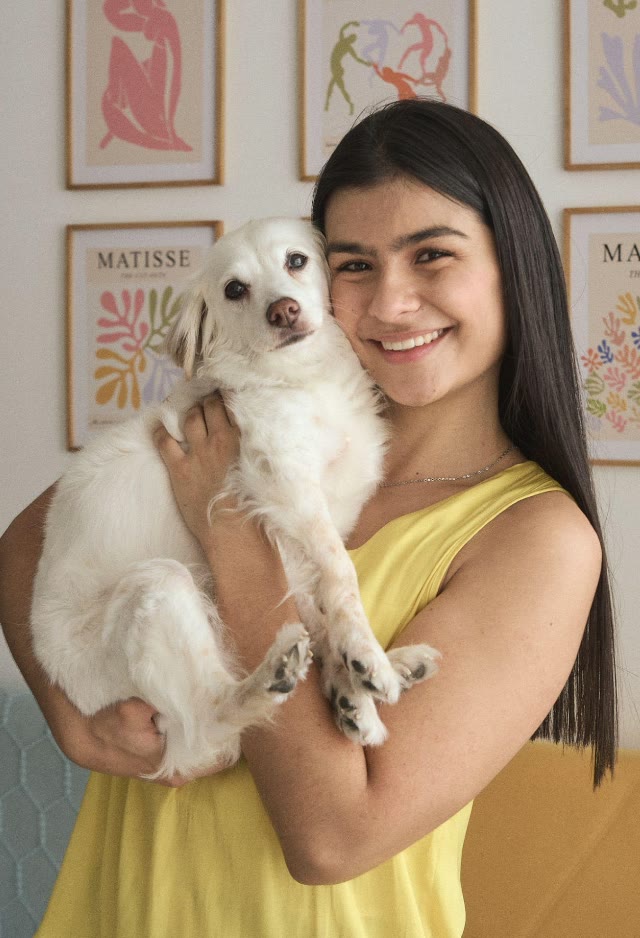 Isabella, comunicadora animal, sostiene en brazos a un perro blanco pequeño